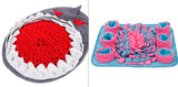 Two textured mats, one shark-shaped and one with pink and blue design, on a white background.