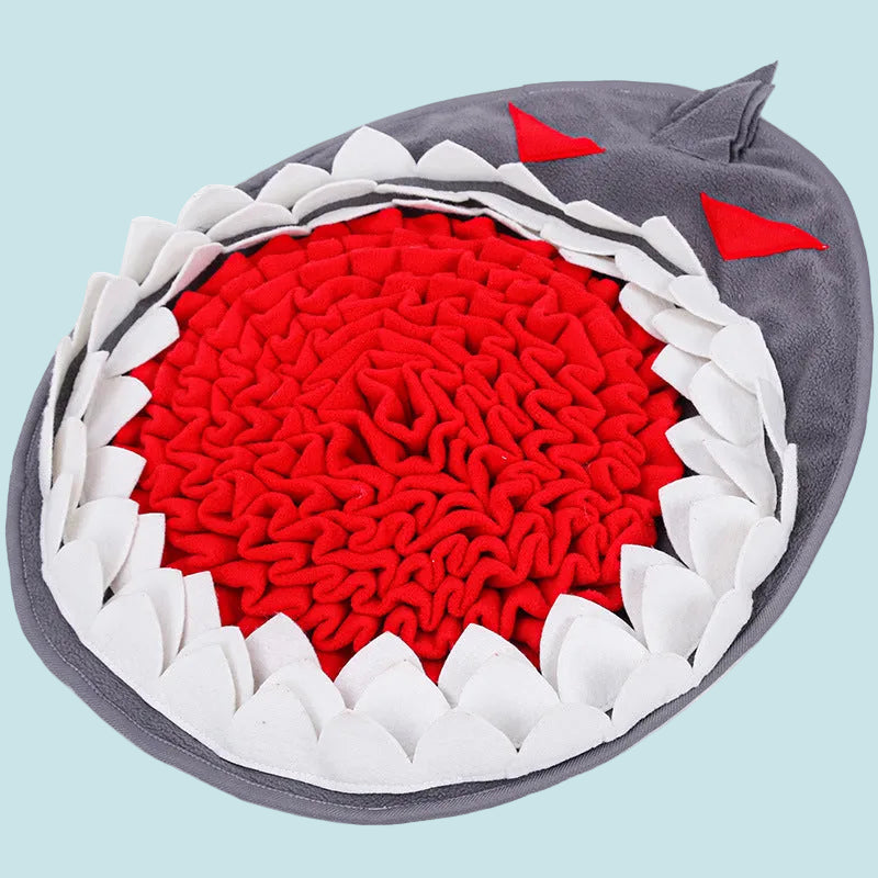 Shark-shaped pet toy with red interior, white spikes, and gray exterior on a white background
